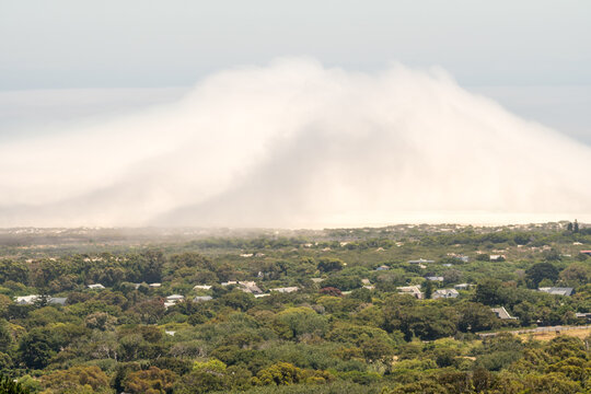 cold front or weather front arriving on land from the sea or ocean forming a large fog cloud as it rolls in over a suburban landscape in Cape Town, South Africa concept weather, seasons, climate
