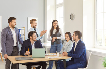 Cheerful and diverse team of a business people working together with a laptop during a meeting in the office. Engaging in negotiations and teamwork to achieve collective work goals.