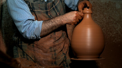 Professional potter making a ceramic vase on the potter's wheel.