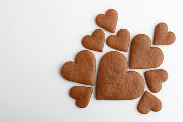 Undecorated heart-shaped gingerbread cookies in three sizes on a white background, copy space for text