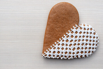 Decorated heart-shaped gingerbread cookie on a light background, copy space for text