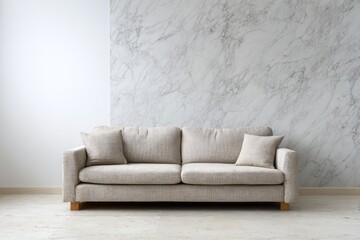 Fototapeta premium Modern neutral sofa placed against a marbled wall creates a chic living space.
