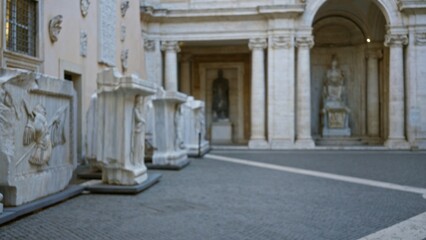 Blurred historic courtyard featuring defocused marble sarcophagi and statues, soft colonnade and cobblestone ground, museum background; background backdrop copyspace calm.