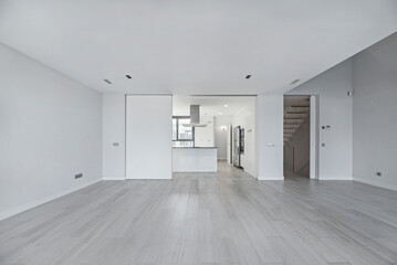 Spacious empty living room with large windows flooding the space with natural light, light wood floors, and high ceilings with exposed beams