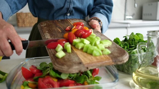 Woman Pouring Chopped Vegetables Like Cucumbers And Tomatoes Into Bowl For Salad