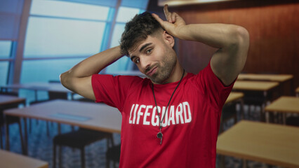 Man wearing red lifeguard shirt and whistle touching head in building classroom; uncertainty doubt...
