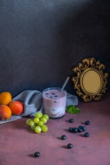 Composition with mountain blueberries and a blueberry and mango smoothie on an aromatic cedar wood board