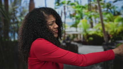 African american woman with curly hair and gritted teeth in red shirt pulling rope gesture with...
