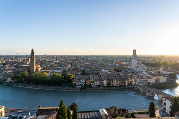 Obraz premium Historic District of Verona Italy with Church Towers as the Sun Sets and Blazes Across the Sky