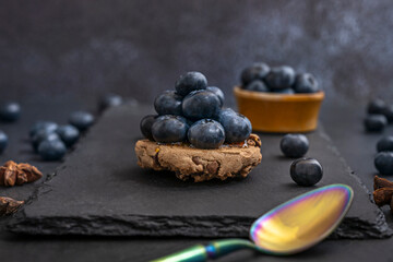 Still life with blueberries on a dark exposed concrete background and a Japanese ceramic spoon with tenmoku glaze