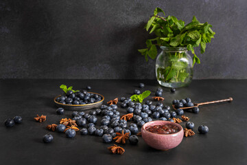 Autumn still life with blueberries on a dark walnut wood background and a natural bone spoon holding shiny fruits