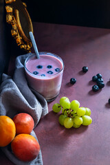 Bowl of perfectly spherical blueberries and a blueberry and pear smoothie on a white oak table
