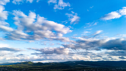 Drone view of a mountain landscape under a bright blue sky with dramatic white clouds — beautiful natural scenery ideal for nature and travel concepts