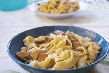 homemade egg pappardelle with porcini mushrooms in blue bowl