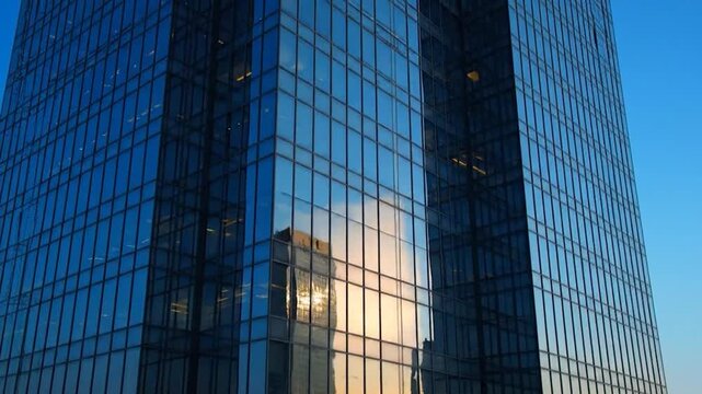 Tall glass skyscraper with reflective windows and clear blue sky