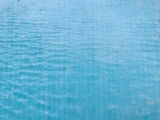Close up of a blue swimming pool water surface with light reflections on a sunny day