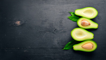 Slice avocado, Fresh avocado with leaves on a black background. Top view. Free space