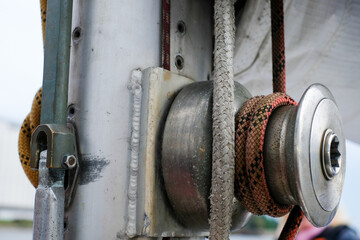 Sailing equipment close-up featuring a metal pulley, rope, and rigging details, showcasing the intricate mechanics of nautical gear and the essence of maritime adventure