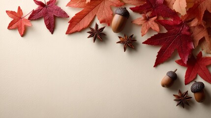 Colorful autumn leaves, acorns, and star anise are arranged on a beige background, forming a beautiful frame with copy space, perfect for fall themed designs