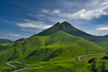 Majestic Mount Yufu in Oita, Japan, with lush green grasslands under a vivid blue sky. Scenic summer landscape of rolling hills and curving roads in the Aso-Kuju National Park, no people, clear weathe