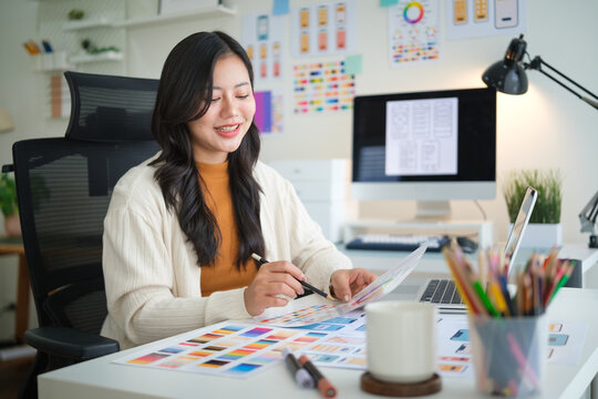 Young web designer analyzing color tones and interface layouts for mobile application development.