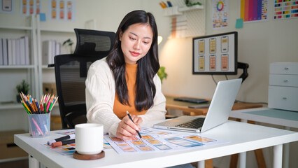 Female web designer studying user interface plans for mobile application at creative workplace.