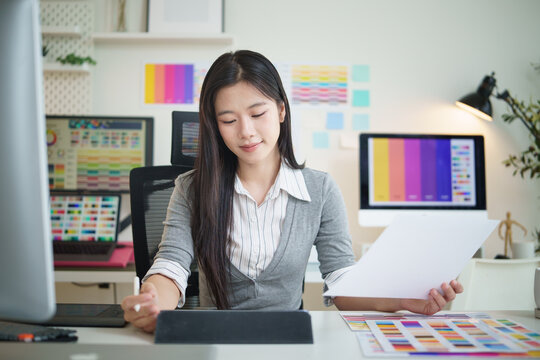 Creative woman working on a design project with stylus and color samples in modern office.
