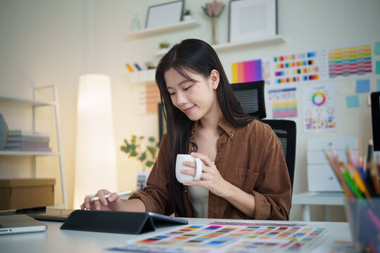 Creative woman working on a design project with stylus and color samples in modern office. - Powered by Adobe