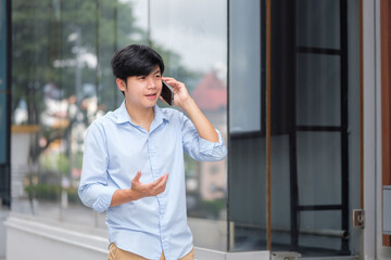 Businessman talking on cell phone near glass building, representing corporate lifestyle and remote work.