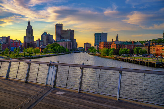 View of downtown Providence and the Providence River at colorful sunset, seen from a pedestrian footbridge in Rhode Island, USA.