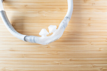 A nasal pillow CPAP mask shot over a wooden surface. The mask is used to give therapy to patiences...