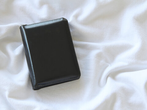 Overhead view of black mockup friendly leather book cover with space for text overlay on a white surface with copy space. 