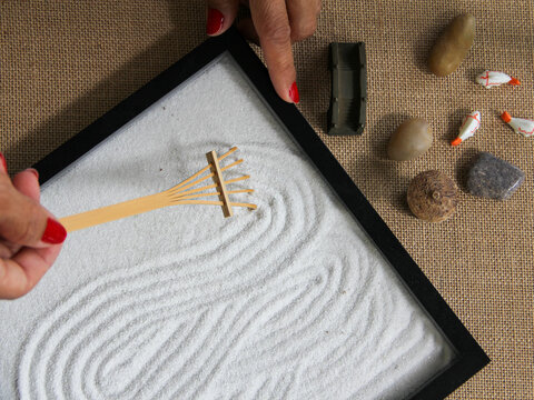 Flat lay overhead of woman meditating with a zen garden helping her to relax and keep her mind healthy for mental heath concept. 