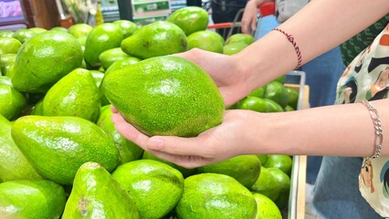 Hand holding avocado at supermarket