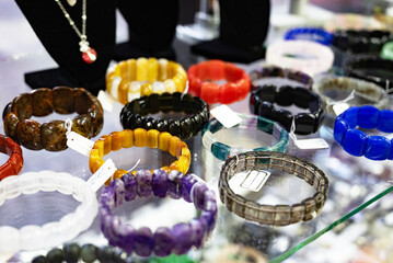Assorted gemstone bracelets displayed on a glass shelf.