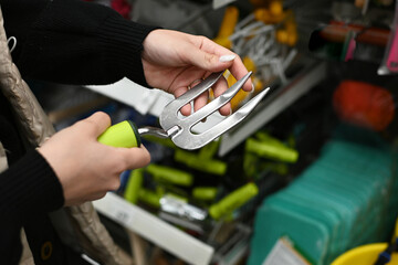 Person examines a gardening knife in a home improvement store during daytime