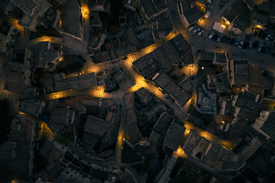 Aerial view of the ancient city's winding streets illuminated by warm, golden lights casting shadows on the timeworn stone buildings, Matera, Basilicata, Italy.