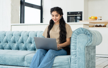 Indian woman student studying at home while sitting on sofa. Distance learning, communication,...