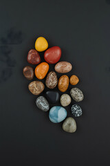 Collection of colorful pebbles arranged on a dark surface, top down view