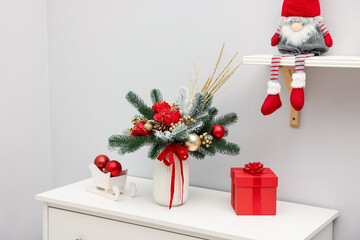 Fototapeta premium Beautiful composition with fir tree branches in vase on white chest of drawers and other Christmas decor indoors