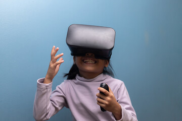 Cheerful Asian girl wearing virtual reality headset and holding controller, smiling while enjoying immersive gaming experience, concept of future technology, learning, and metaverse.