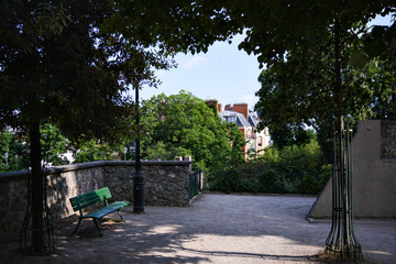 Scenic view of a peaceful street with green trees and benches in Montmartre district of Paris France on a sunny summer day, calm atmosphere and European architecture