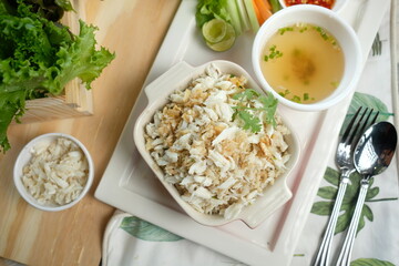 Delicious crab rice with a side of soup and fresh vegetables, a culinary delight. The dish is presented on a wooden board, ready to be enjoyed
