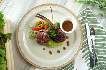 Elegant presentation of a rack of lamb with sides, meticulously plated on a ceramic dish