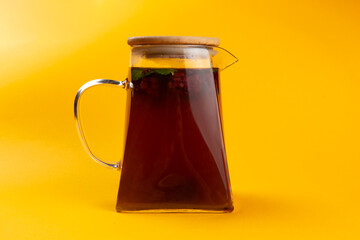 Fruity tea in a teapot on a yellow background.