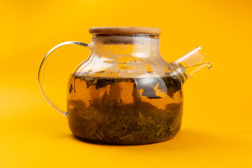 Fruity tea in a teapot on a yellow background.