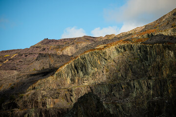 Layered quarry cliffs under a clear blue sky in Snowdonia, Wales