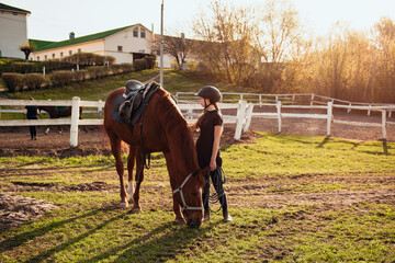 Young girl in equestrian gear enjoys a serene moment grazing a beautiful black horse in a green field, demonstrating the joy and connection between horse and rider.