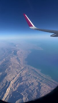 Mountains seen from an airplane window. Airplane wing seen from an airplane window.