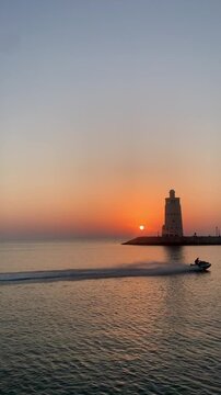 Sunset at sea. View of an old lighthouse at sunset.